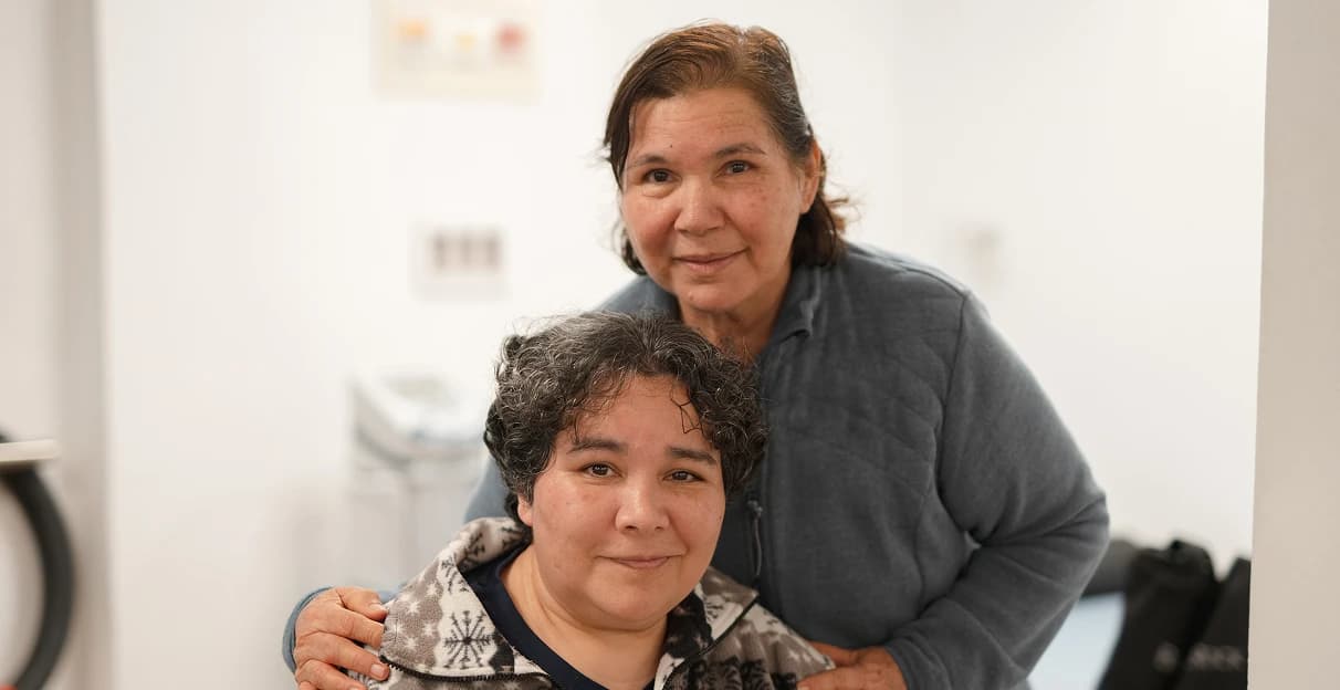 Madre e hija sonriendo abrazadas en el centro.