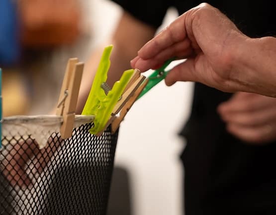 Imagen de unas manos colocando pinzas de colores durante un ejercicio de destreza manual.